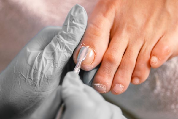 Pedicure behandelt teennagels van klant met instrument